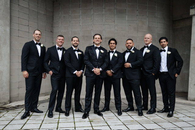 Wedding party in dark suits in a stone courtyard