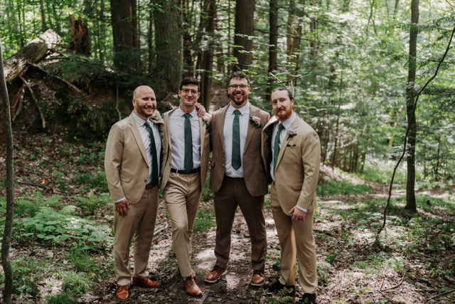 Four members of a wedding party in tan suits in woodland